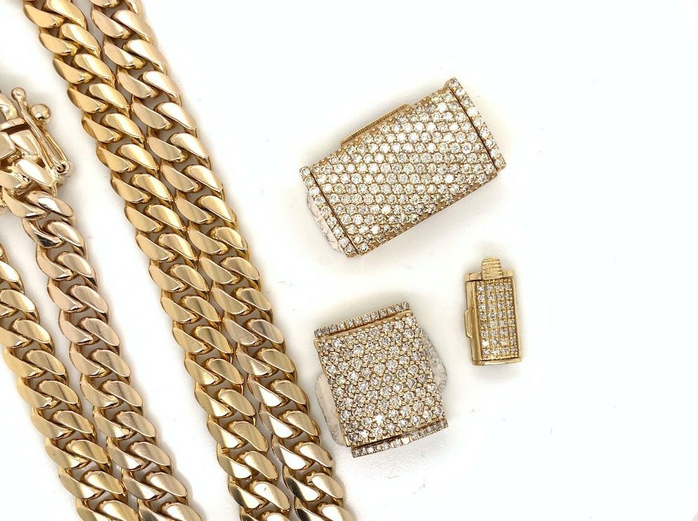 Cuban link gold chains and diamond rings on white backdrop
