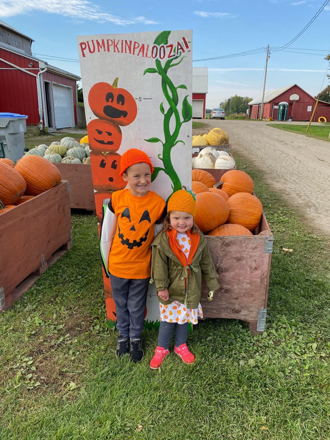 A boy and a girl are posing for a picture at a pumpkin patch.