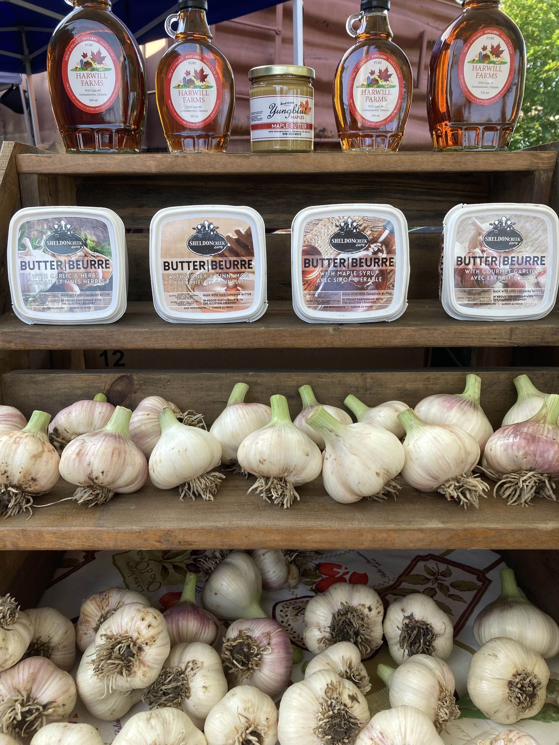 A shelf filled with garlic and maple syrup.