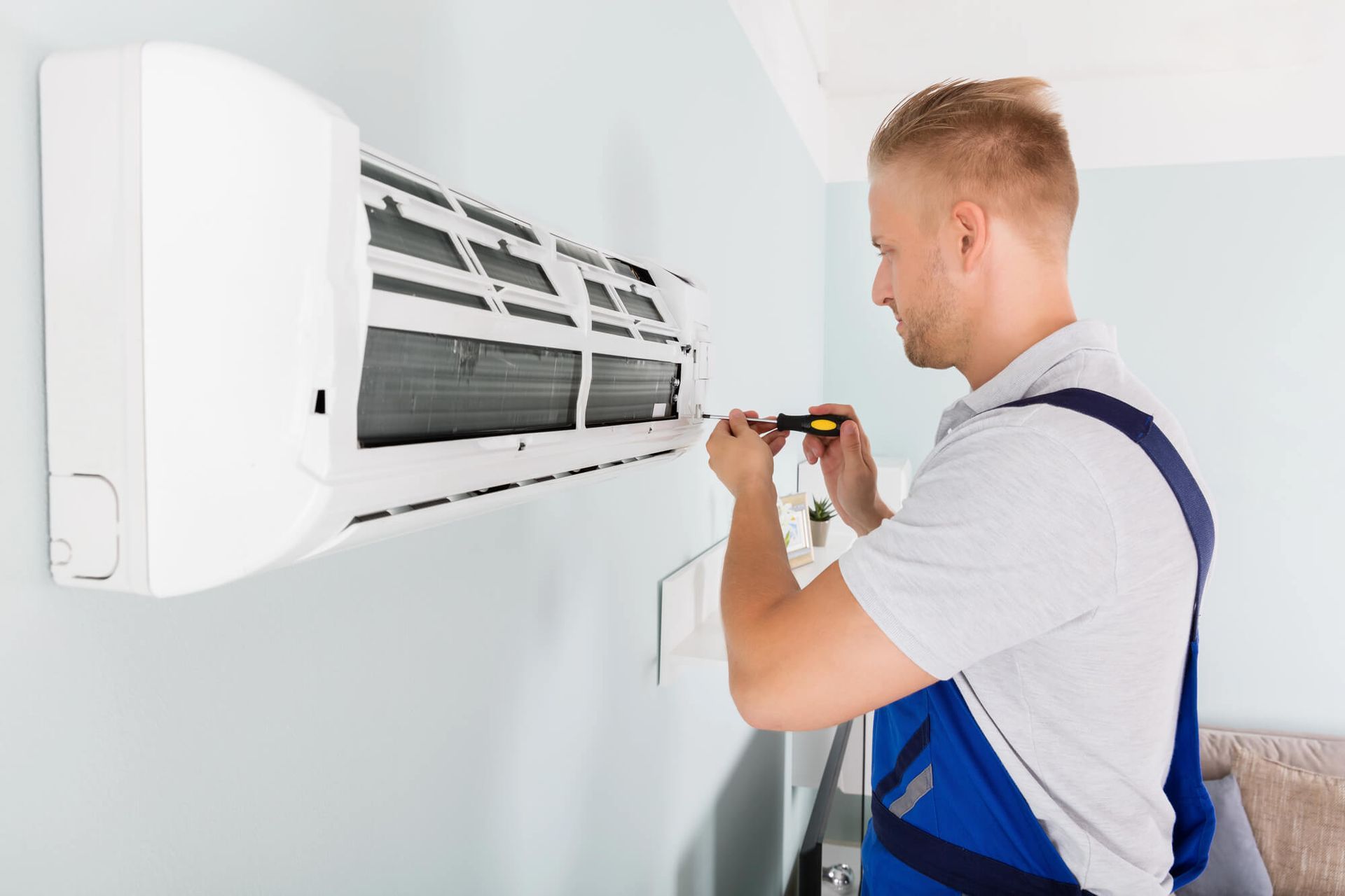 A man is installing an air conditioner on a wall.