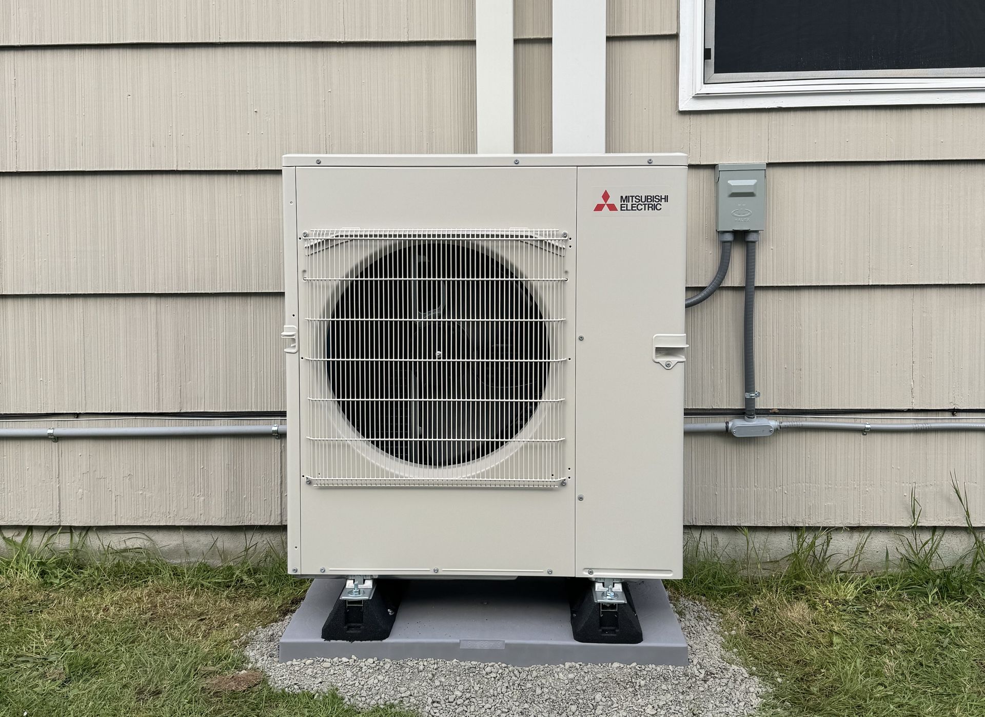 A white air conditioner is sitting on the side of a house.