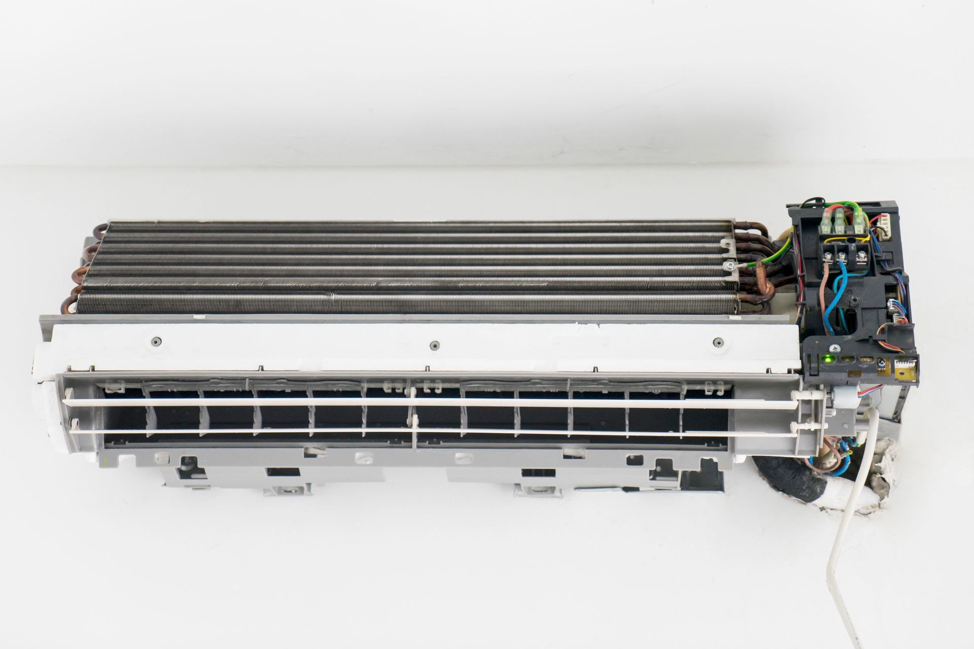 A close up of amn uncovered air conditioner on a white wall.