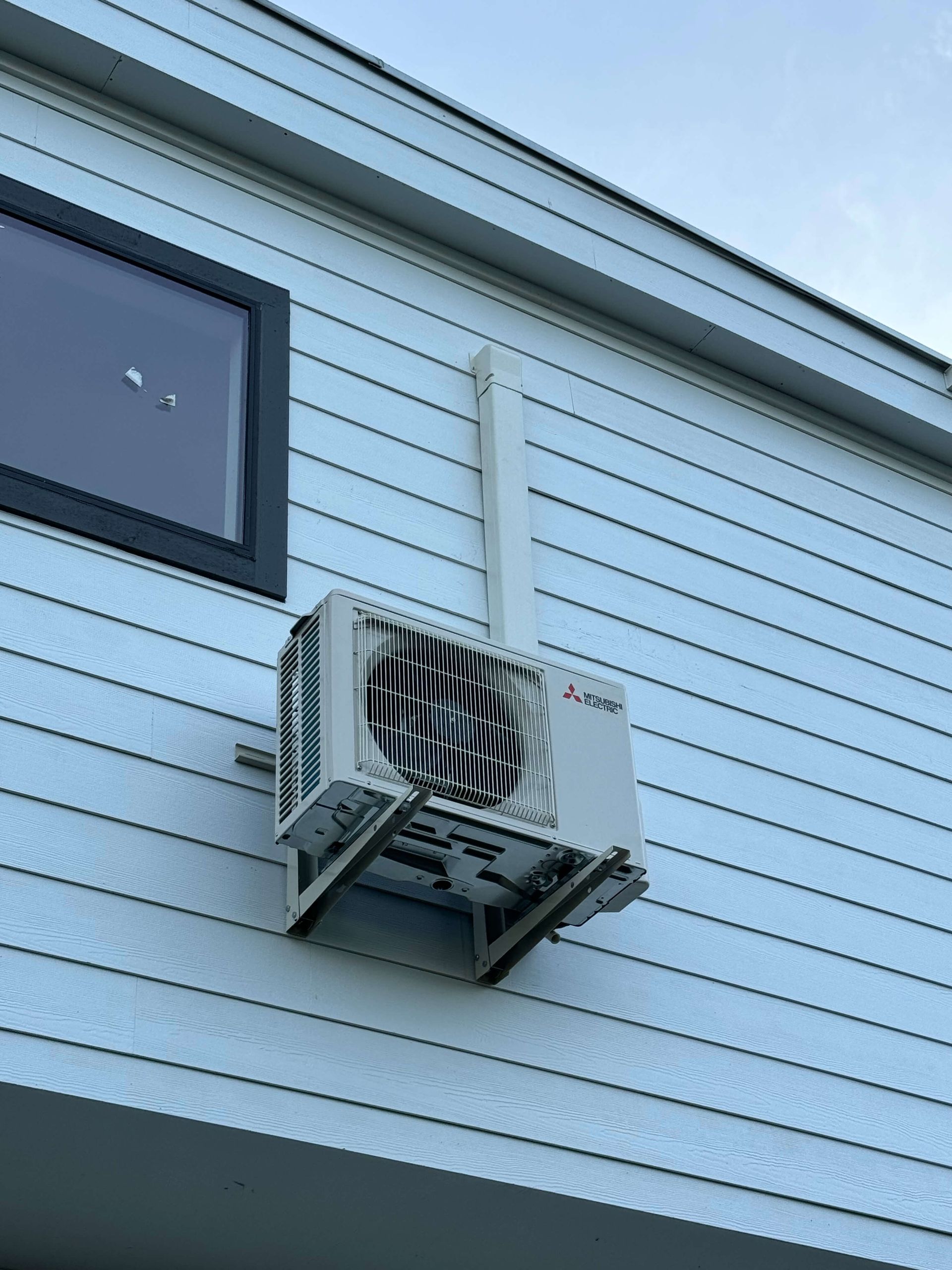 A white air conditioner is mounted on the side of a building.