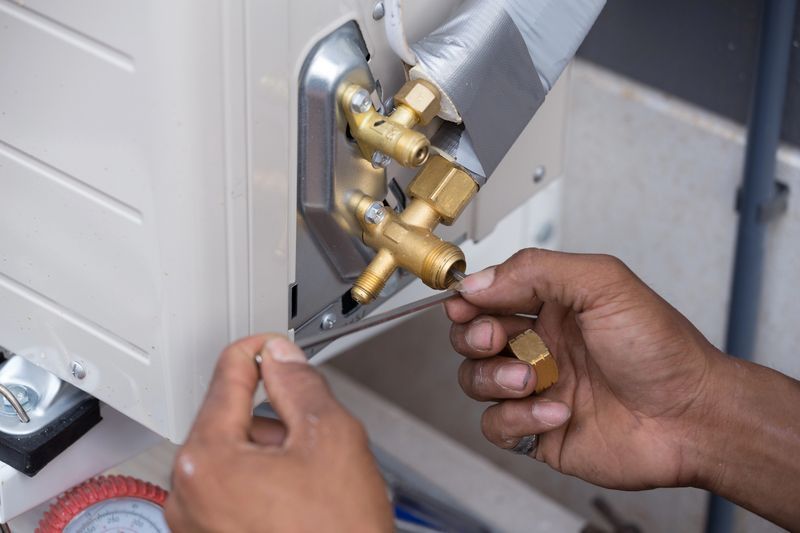 A man is fixing an air conditioner with a screwdriver.