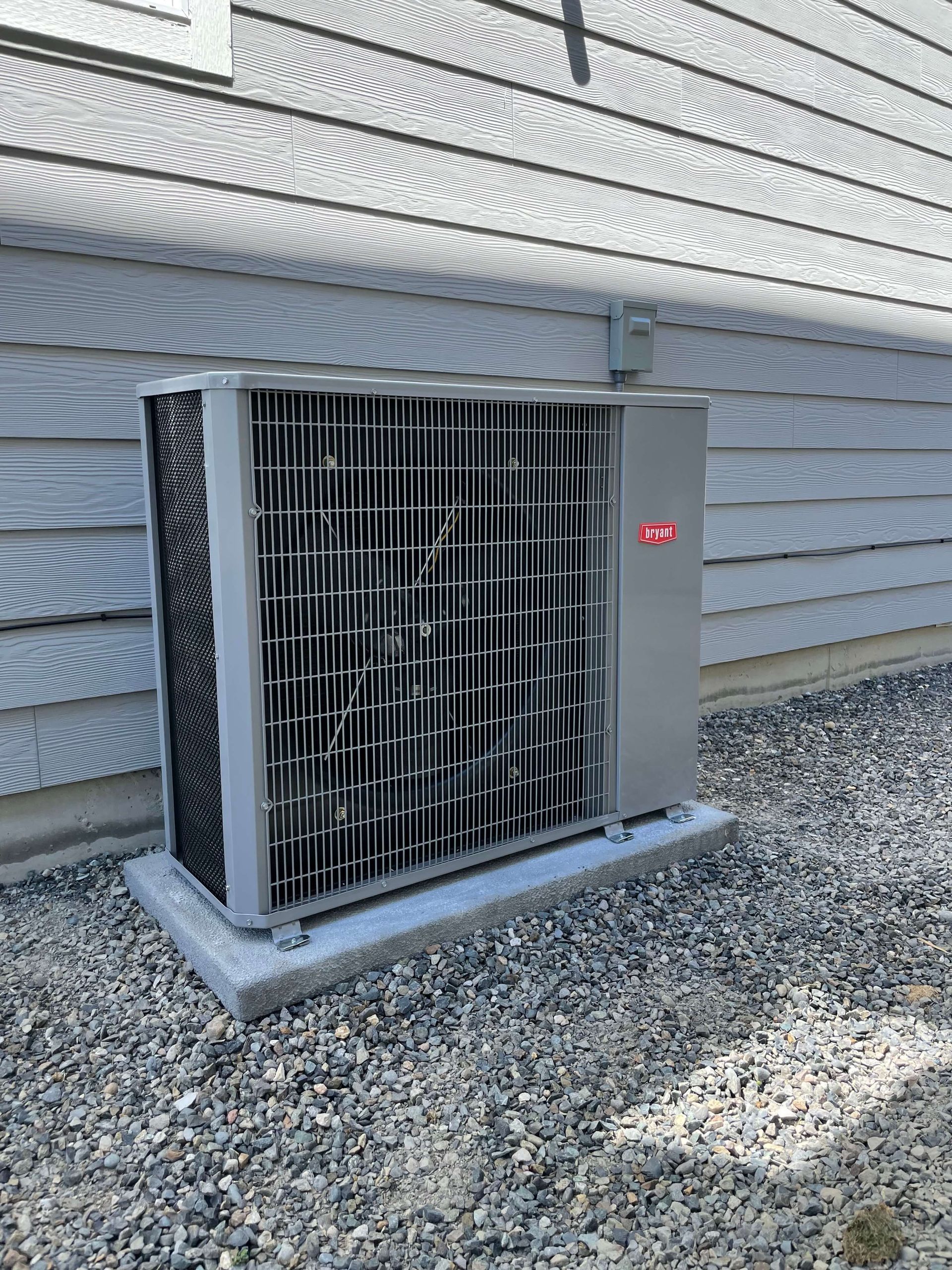 A large air conditioner is sitting outside of a house.
