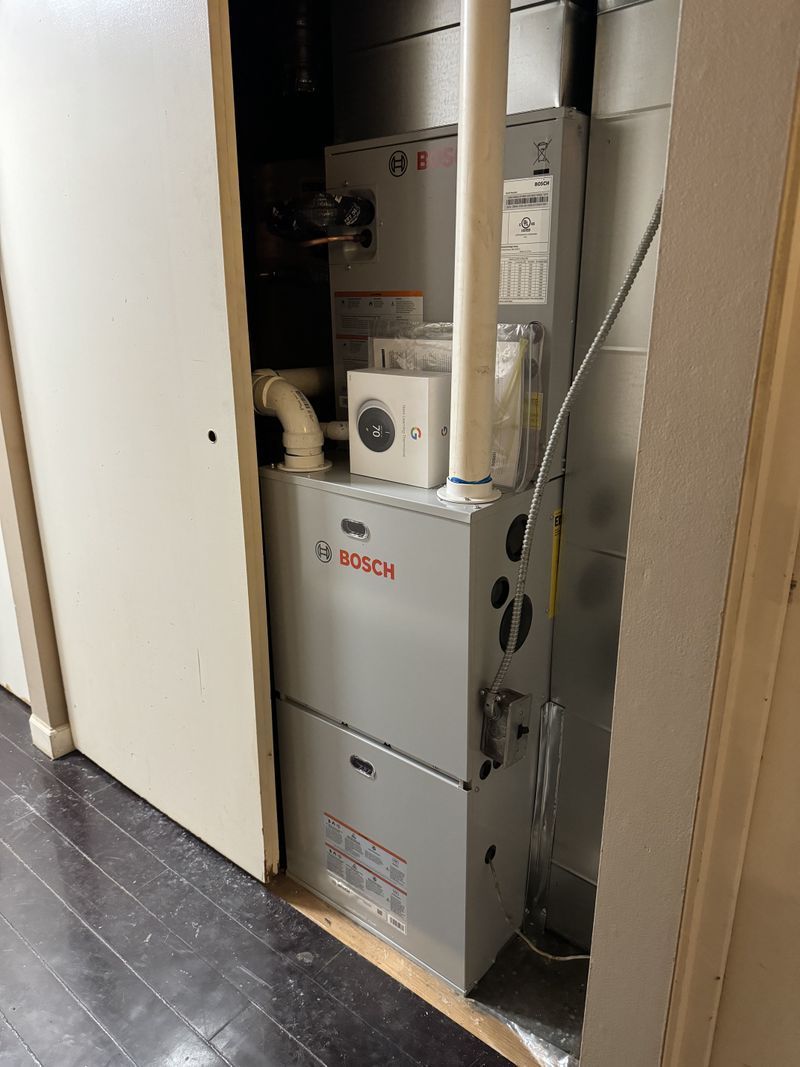 A furnace is sitting in a closet next to a door.