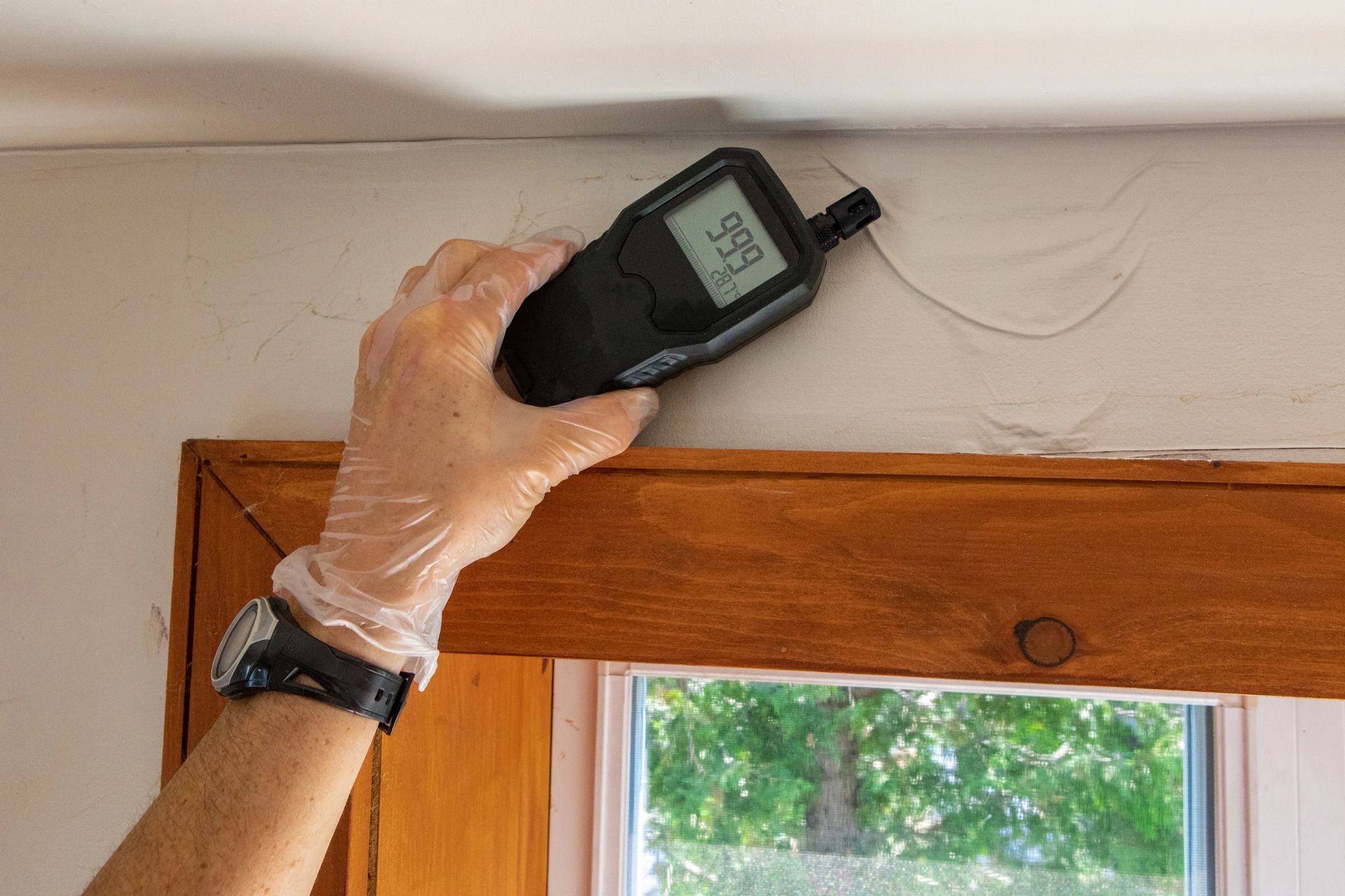 A person is using a digital thermometer to measure the humidity of a room.