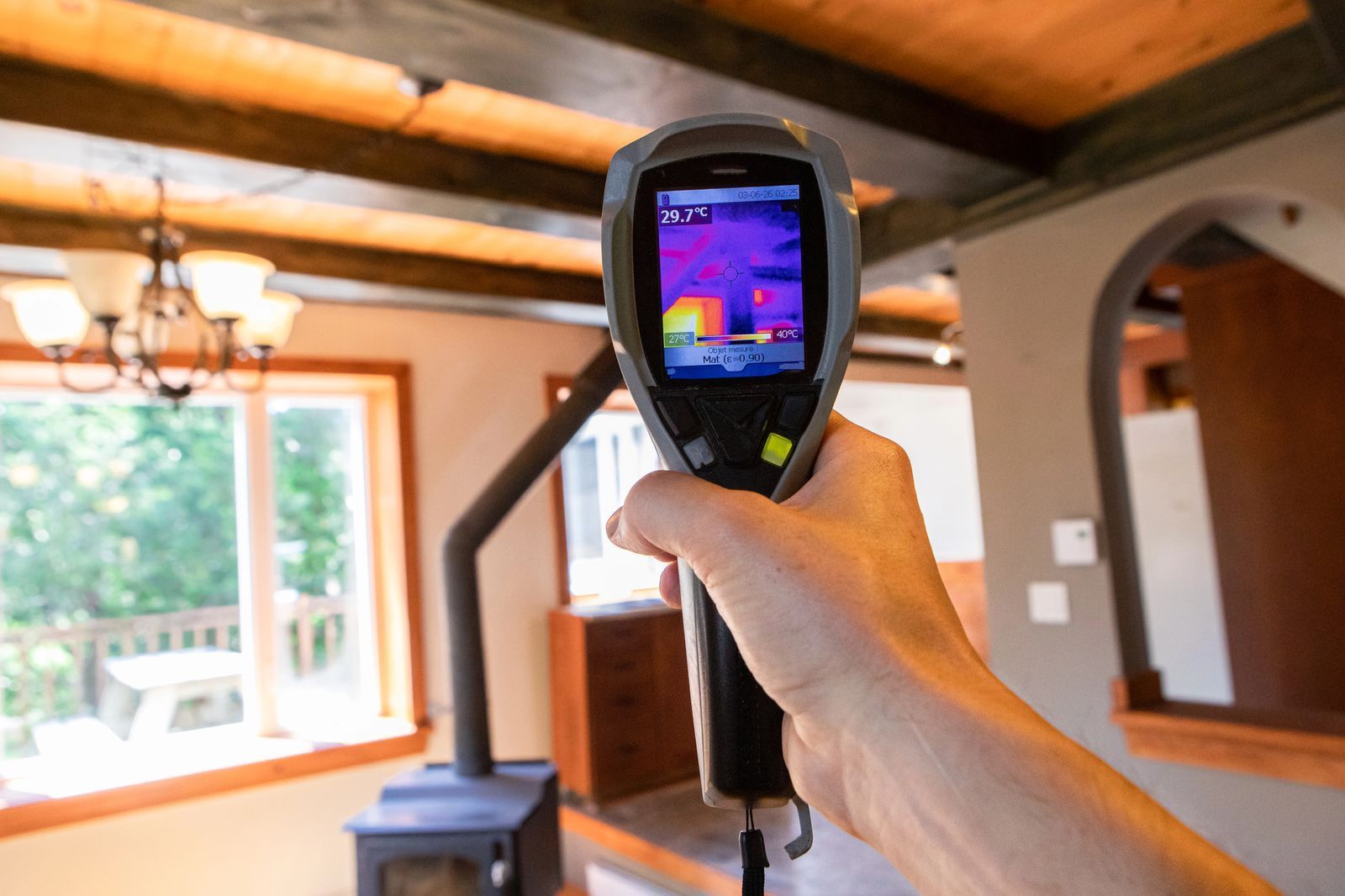 A person is holding a thermal camera in a living room.