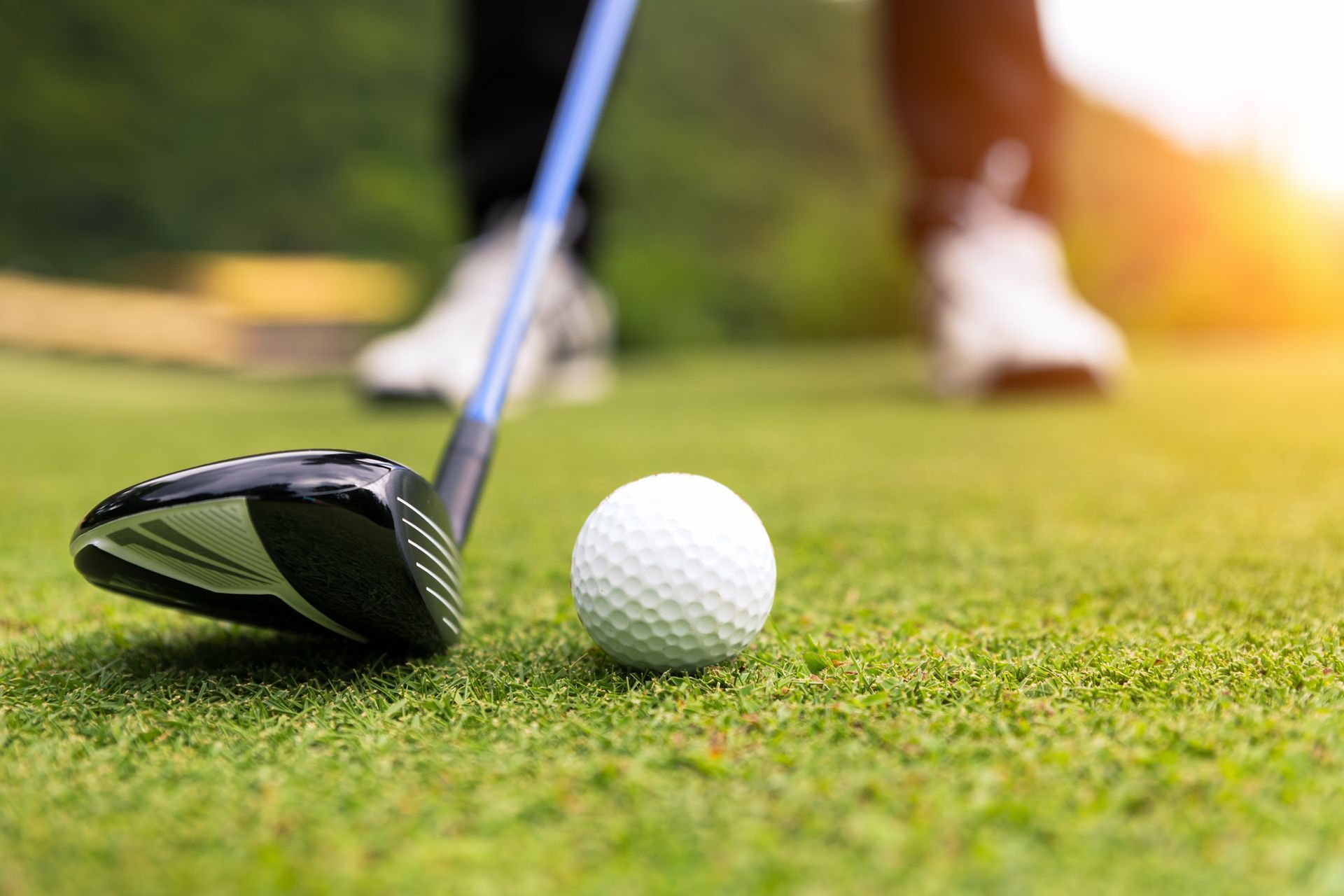 A person is hitting a golf ball with a golf club on a golf course.