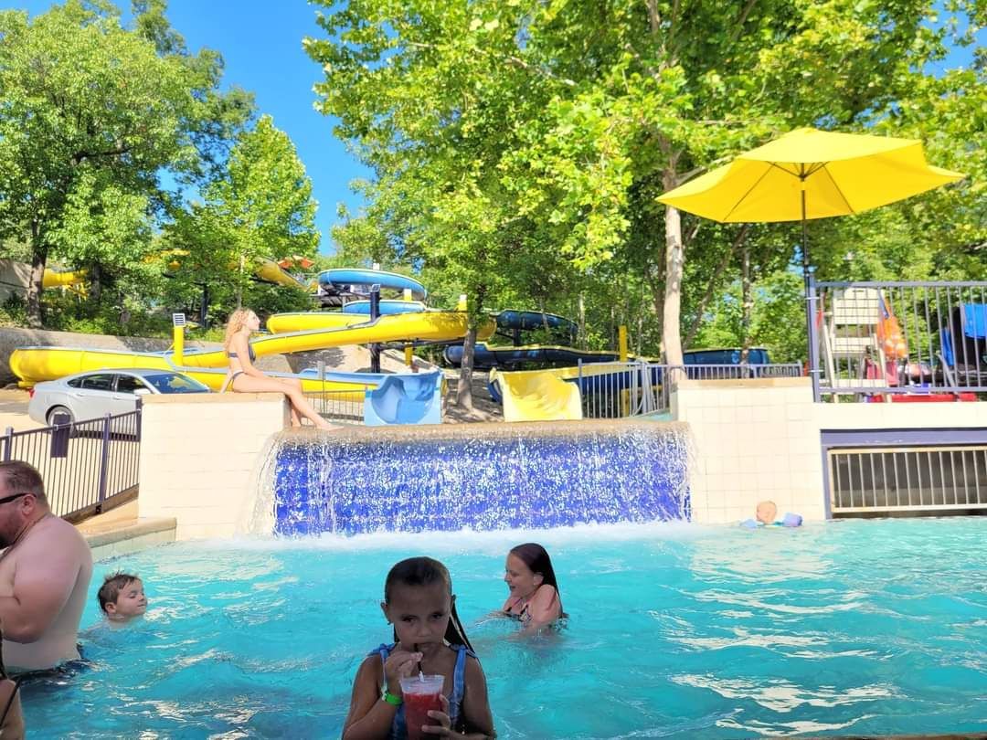 A group of people are swimming in a pool at a water park.