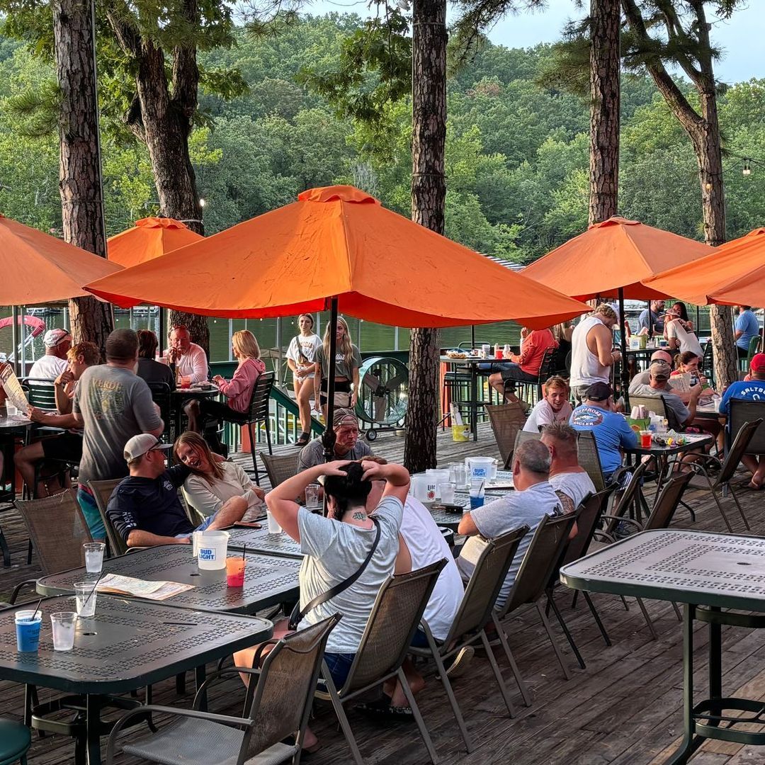A group of people are sitting at tables under orange umbrellas