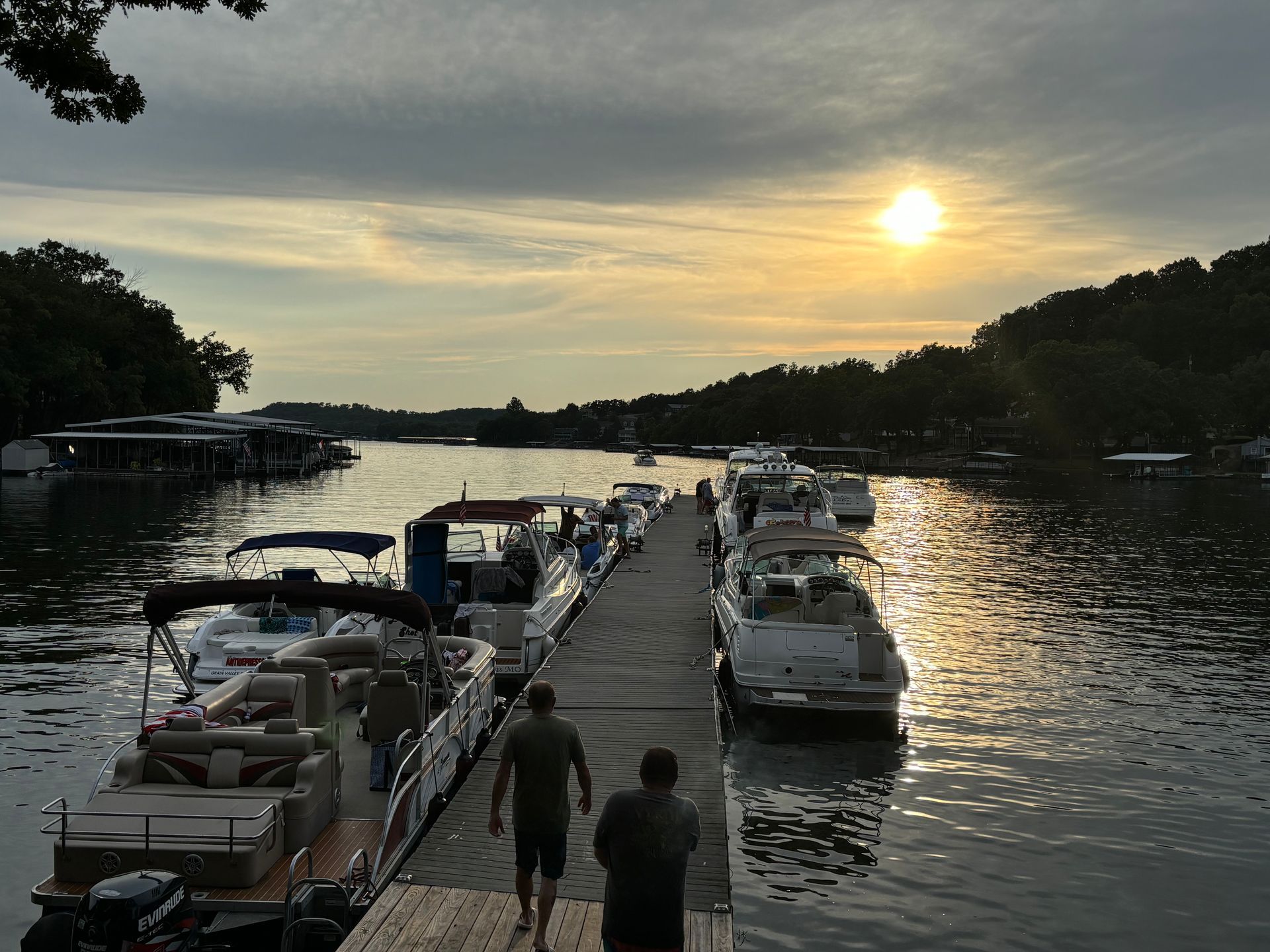 A couple of people standing on a dock next to boats.