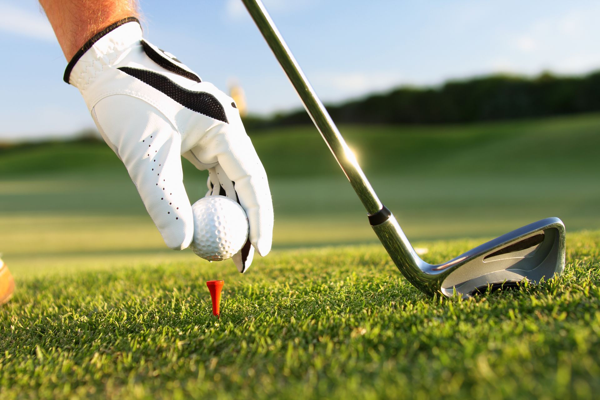 A golfer is putting a golf ball on a tee.