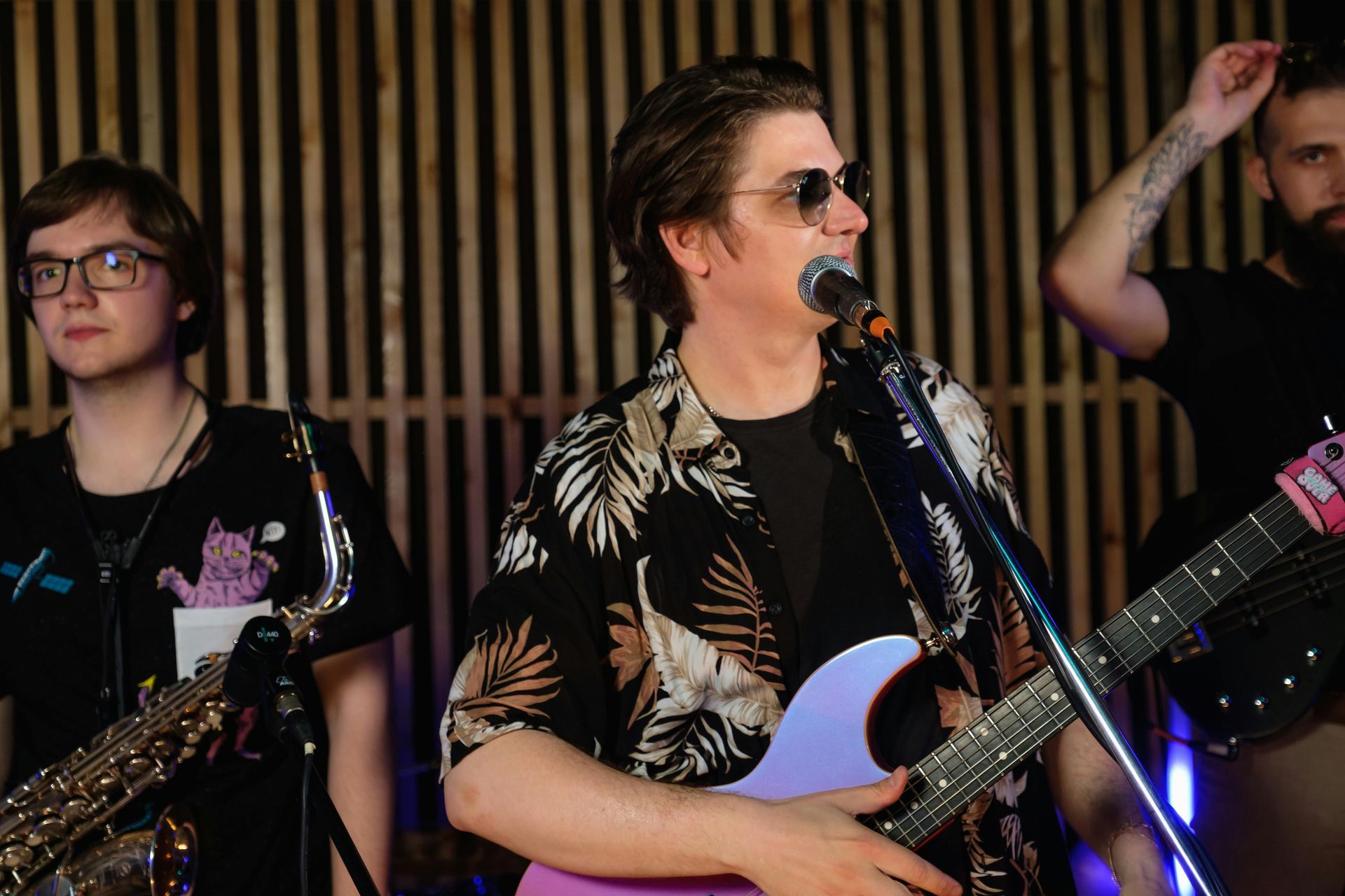 A man is singing into a microphone while playing a guitar in a band.