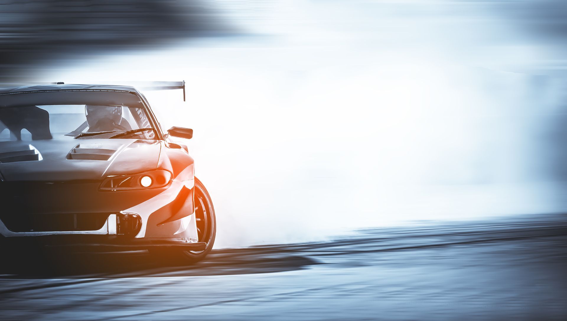 A drift car racing on a track, kicking up a large cloud of smoke with motion blur.