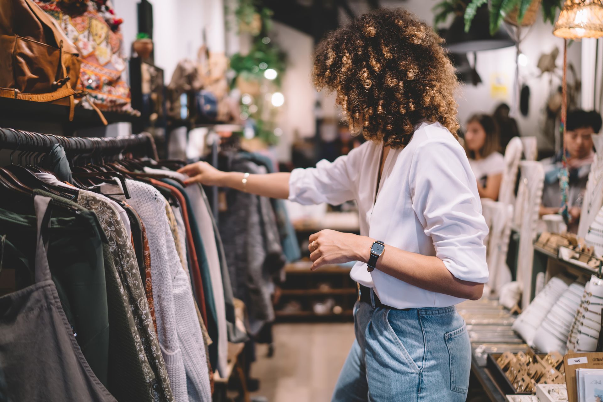 Woman shopping, looking at clothes on a rack in a store.