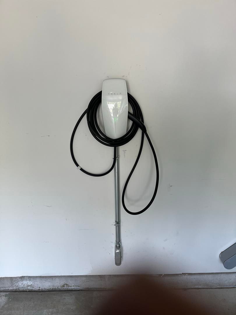 A white wall with a black cord hanging from it.