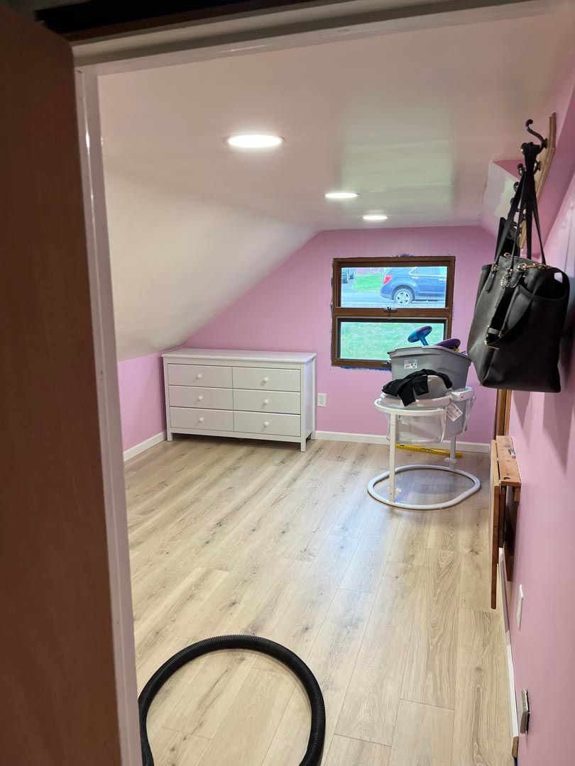 A room with pink walls and wooden floors and a purse hanging on the wall.