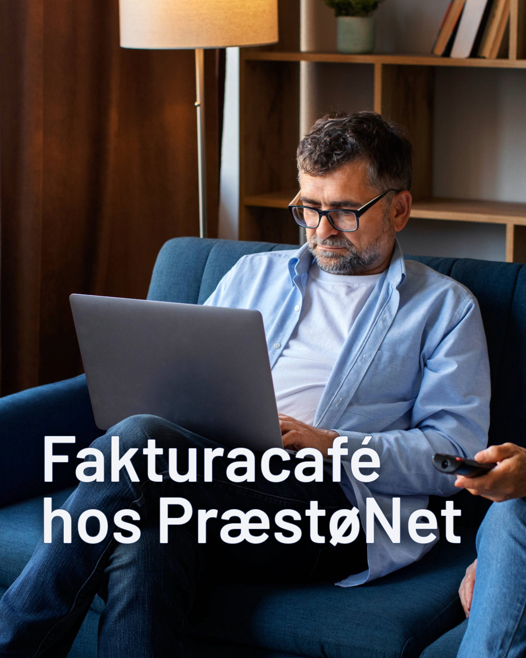 En man der sidder på en blå sofa og har en fjernbetjening i hånden