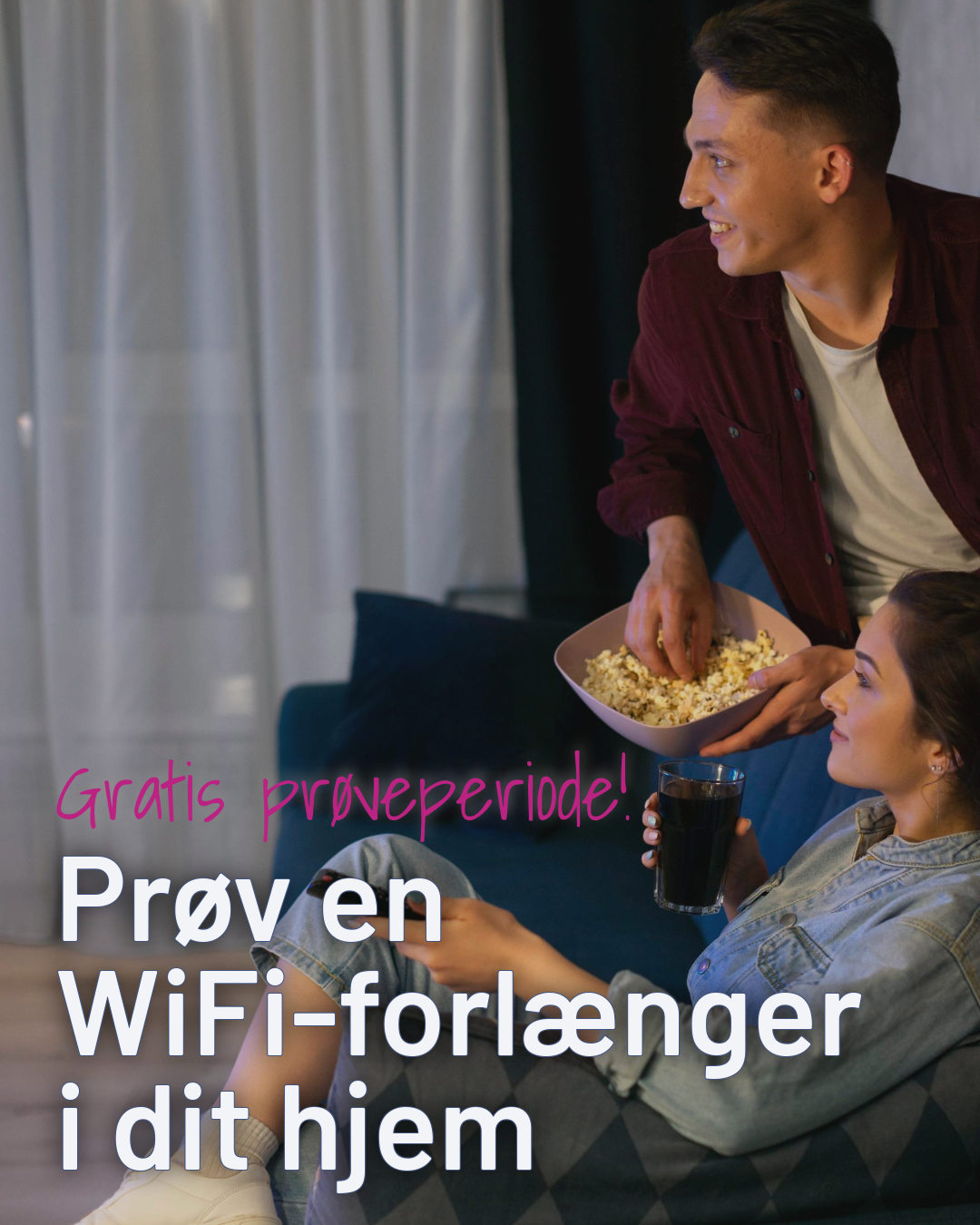 En mand sidder på kanten af sofaen og spiser popcorn. En kvinde sidder i med en fjernbetjening i hånden