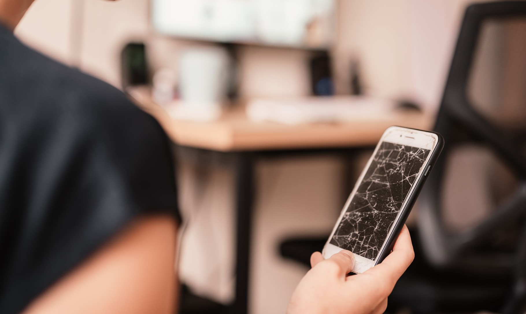 Kvinde ligger på en sofa og kigger på sin telefon imens hun smiler