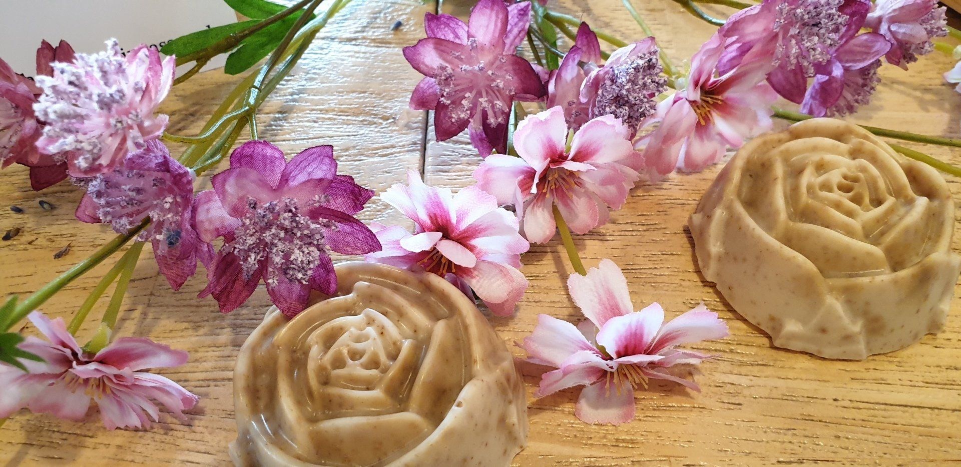 Drie zepen in de vorm van rozen staan ​​op een houten tafel omringd door bloemen.