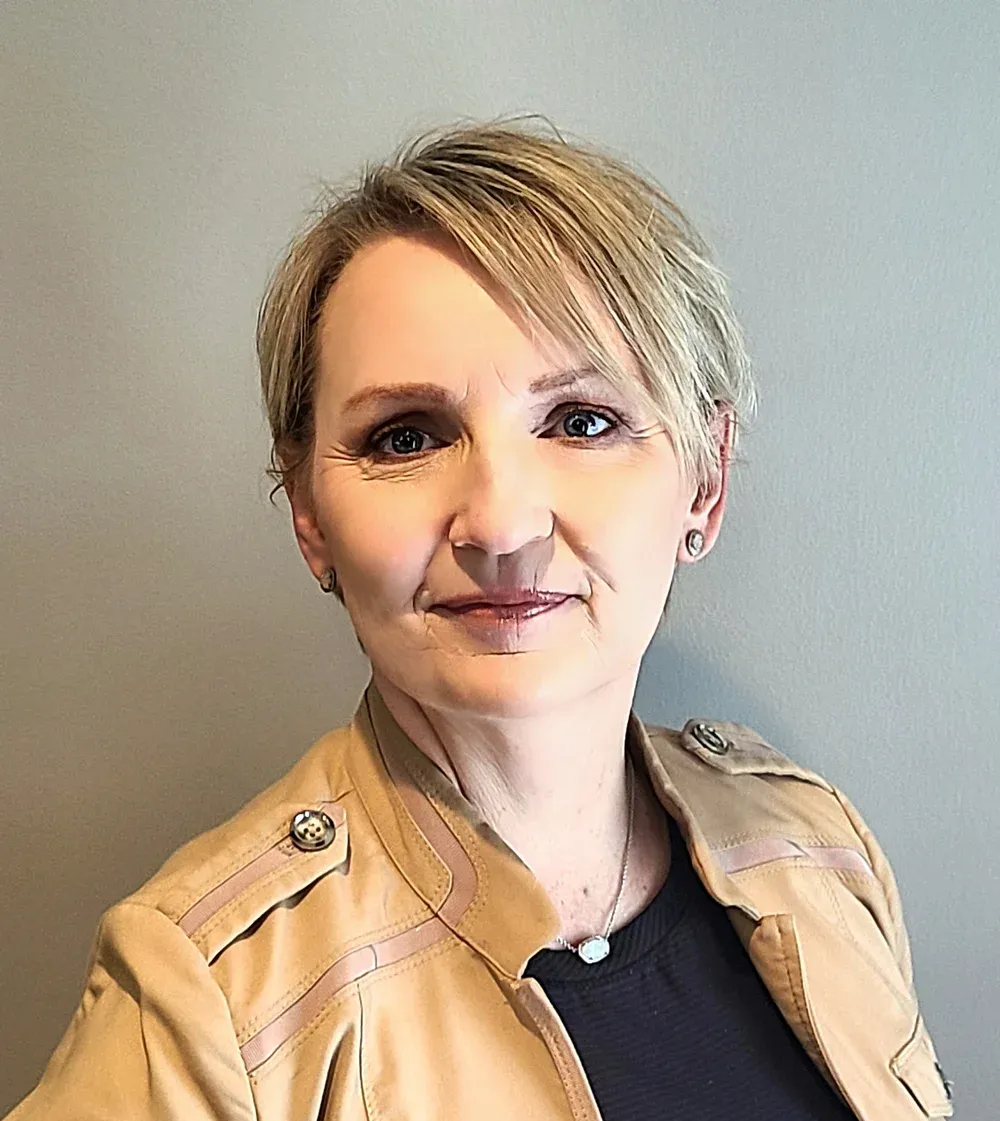 A man in a suit and tie is smiling in front of a window