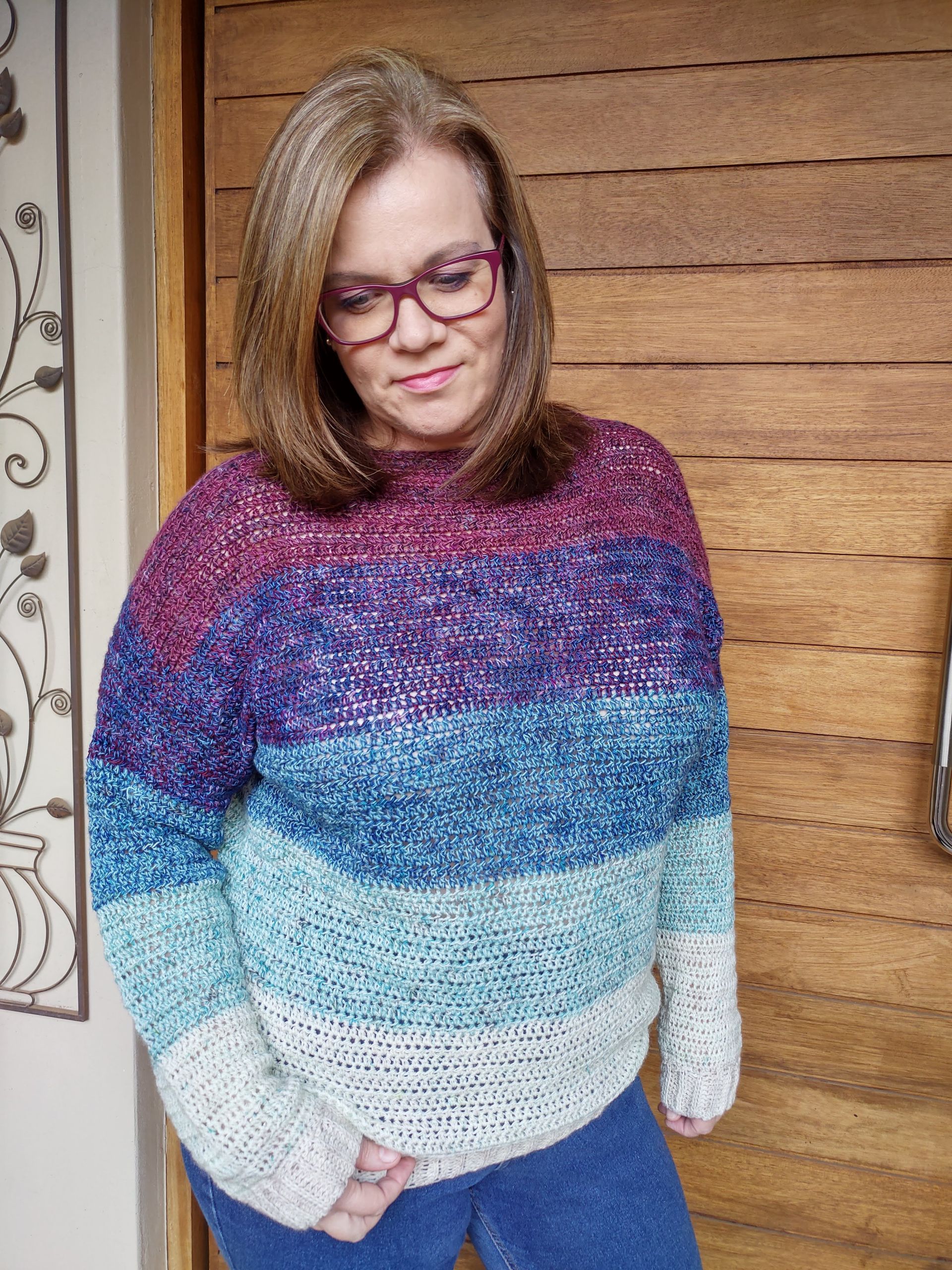 Woman in glasses wearing a colorful striped sweater.