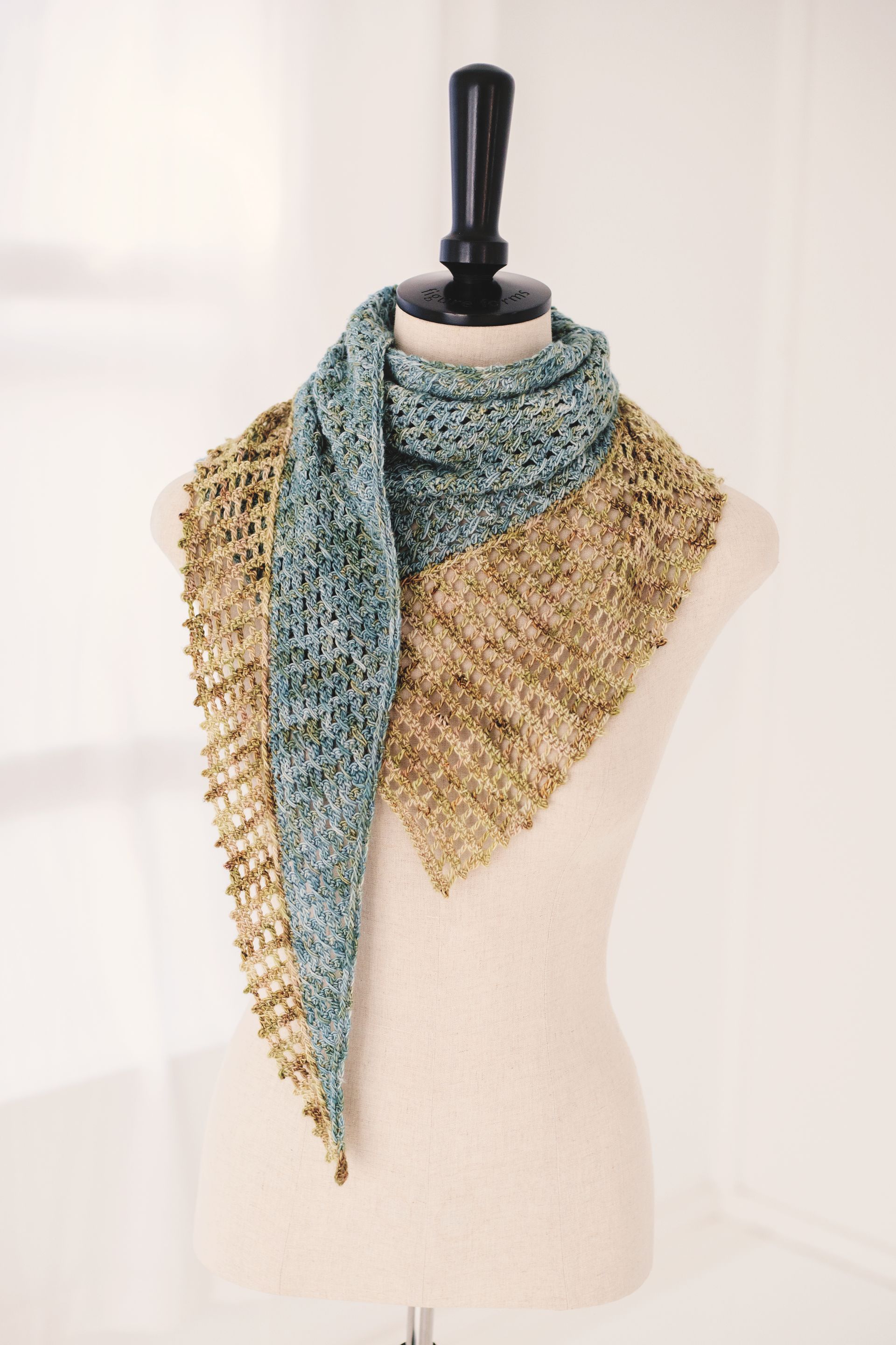 A two-toned shawl on a mannequin: blue and tan, with a triangular shape.