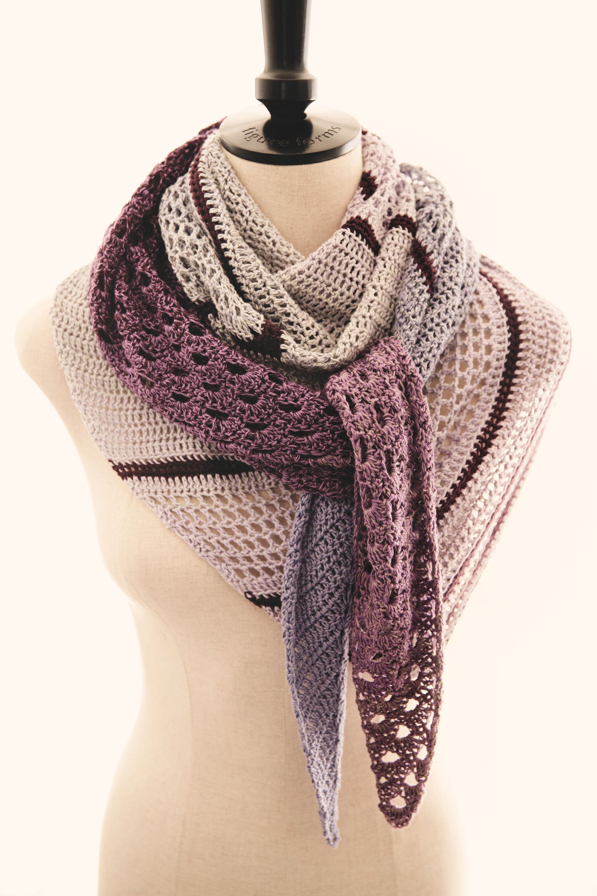 Crocheted shawl in shades of purple and gray draped on a mannequin.