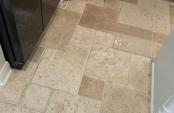 A tiled floor in a kitchen next to a refrigerator.