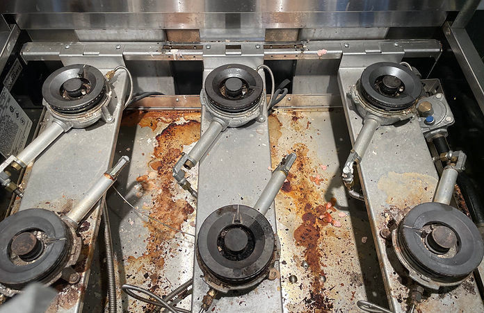 A row of stove burners are lined up on a dirty stove top.