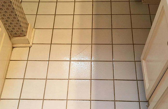 A bathroom floor with white tiles and a white cabinet.