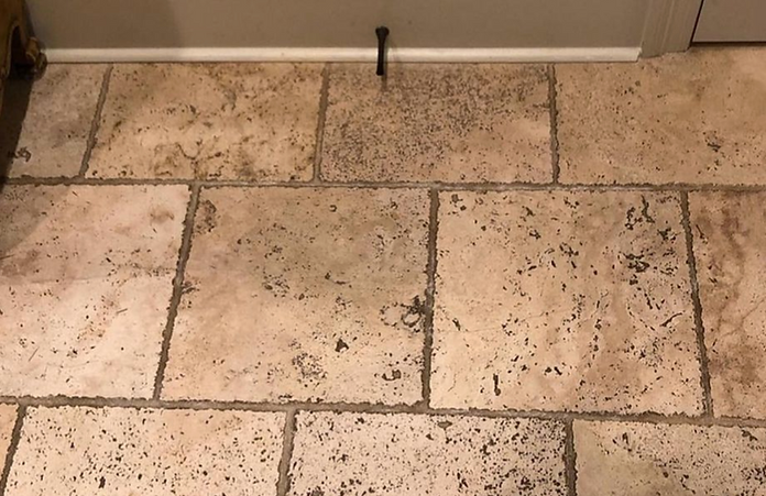 A close up of a tiled floor with a door stop on it.