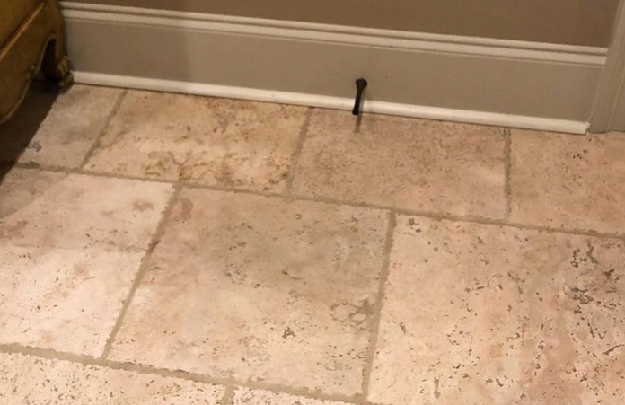 A tile floor with a door stop on it.