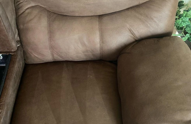 A close up of a brown leather recliner in a living room.