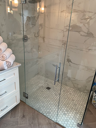 A bathroom with a walk in shower with a glass door.