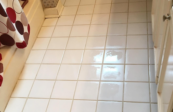 A bathroom with white tiles and a shower curtain