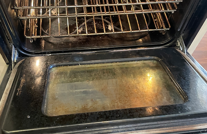 The inside of a dirty oven with the door open.