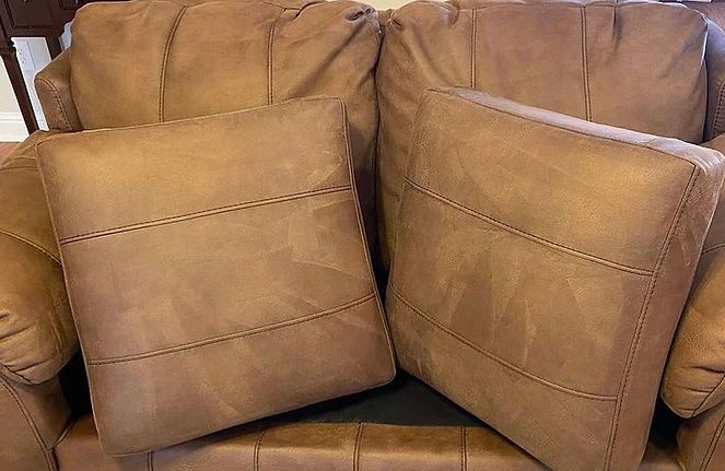 A brown leather couch with two pillows on it.