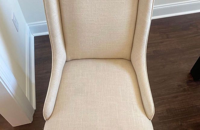 A white chair is sitting on a wooden floor in a room.