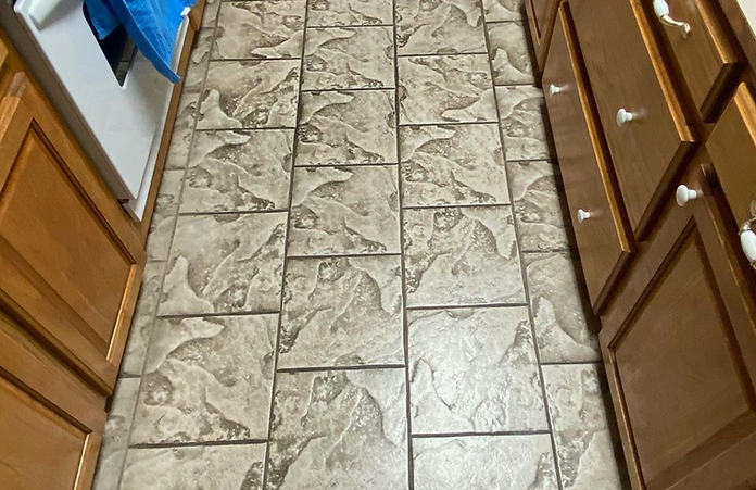 A kitchen with a tiled floor and wooden cabinets.