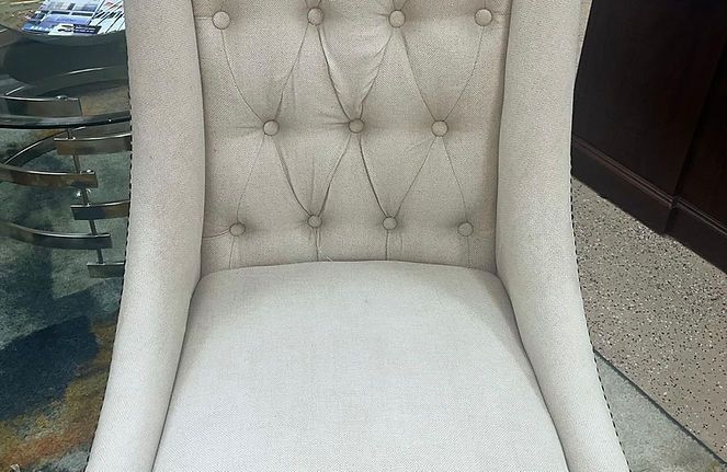 A white chair is sitting in front of a glass table.