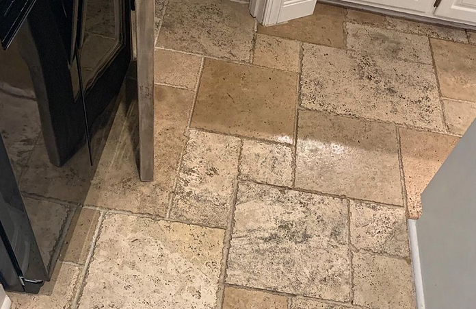 A tile floor in a kitchen next to a refrigerator.