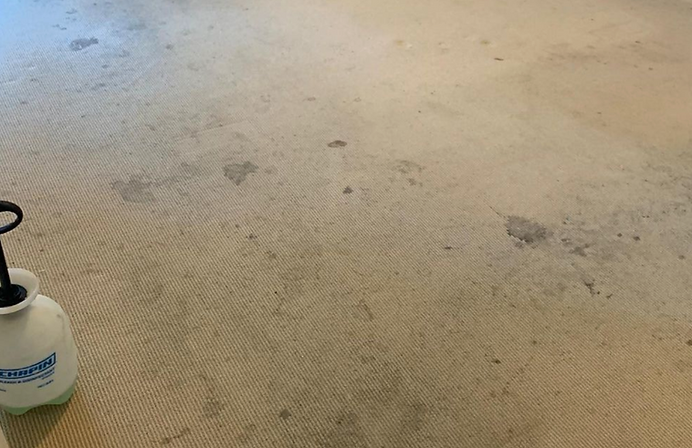 A dirty carpet with stains on it and a spray bottle on the floor.