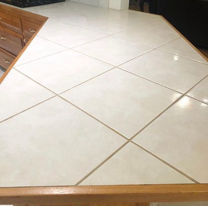 A kitchen counter with white tiles and wooden cabinets.