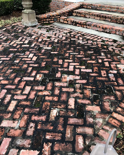 A close up of a brick walkway with stairs in the background.