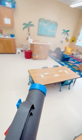 A classroom with tables and chairs and a vacuum cleaner in the foreground