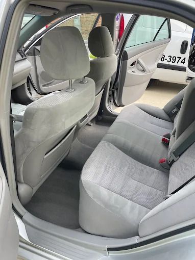 Interior of a silver car with gray cloth seats. The back door is open.
