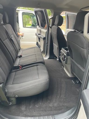 Interior view of a silver truck with black seats and carpet. Rear seats are visible, door open.